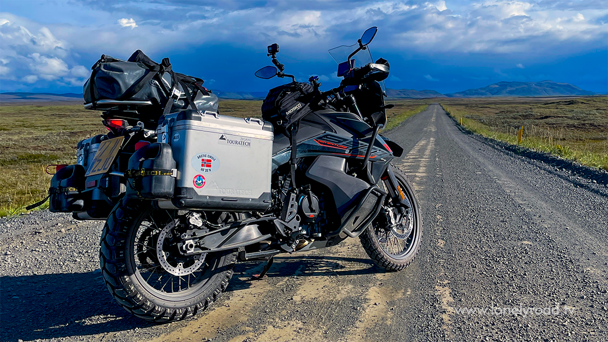 Rear side view of KTM 890 Adventure motorcycle on remote road with luggage.