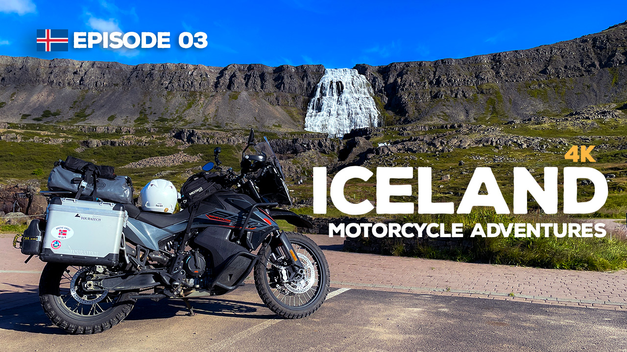 A photo of a KTM 890 Adventure motorcycle parked in front of the Dinjandi waterfall in the Westfjords, Iceland.