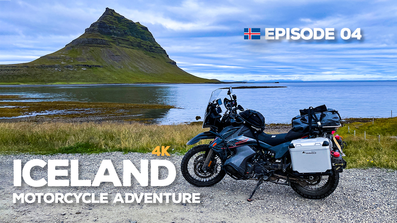 A photo of a KTM 890 Adventure motorcycle, parked on a gravel road in Iceland, with mountains in the distance.