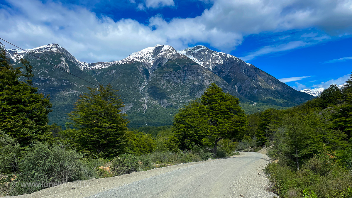 A gravel road with snowcapped mountains in the background