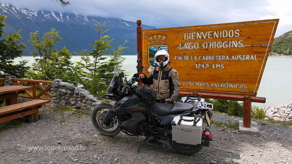 A photo of a KTM 890 Adventure motorcycle and rider in front of the Carretera Austral end of the road sign